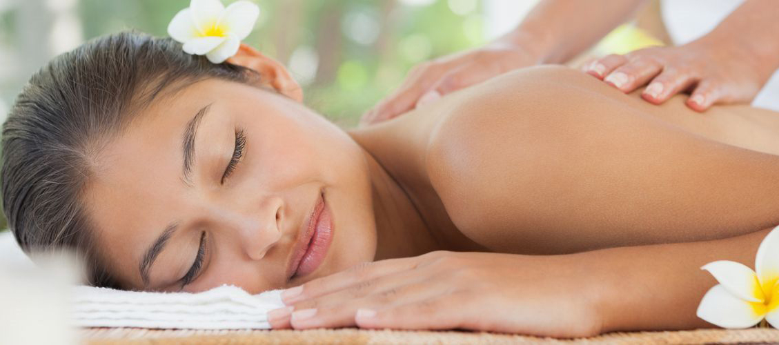 woman with flower in her hair enjoying a massage