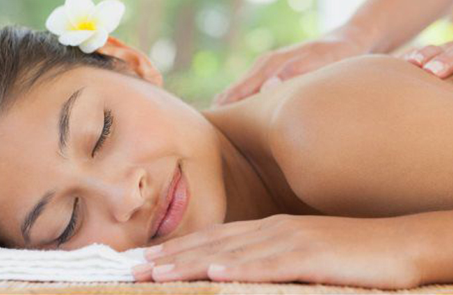 woman with flower in her hair enjoying a massage